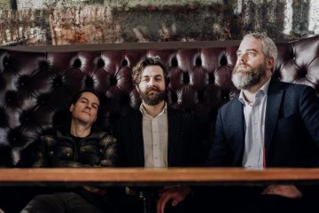 press photo of All the Saints sitting in a booth in a bar.