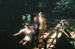 members of floral print standing on a bridge in the woods.