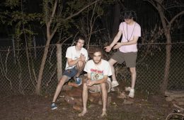 press photo of Fuiste sitting and standing around a rock in the woods.