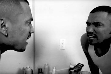 Victor Mariachi looking into a bathroom mirror.