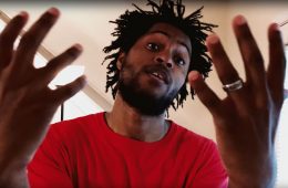 WesdaRuler wearing red t-shirt, rapping into the camera.
