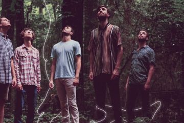 members of Rujen standing in the woods and looking up.