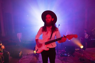 Matthew Pendrick wearing cowboy hat and playing guitar