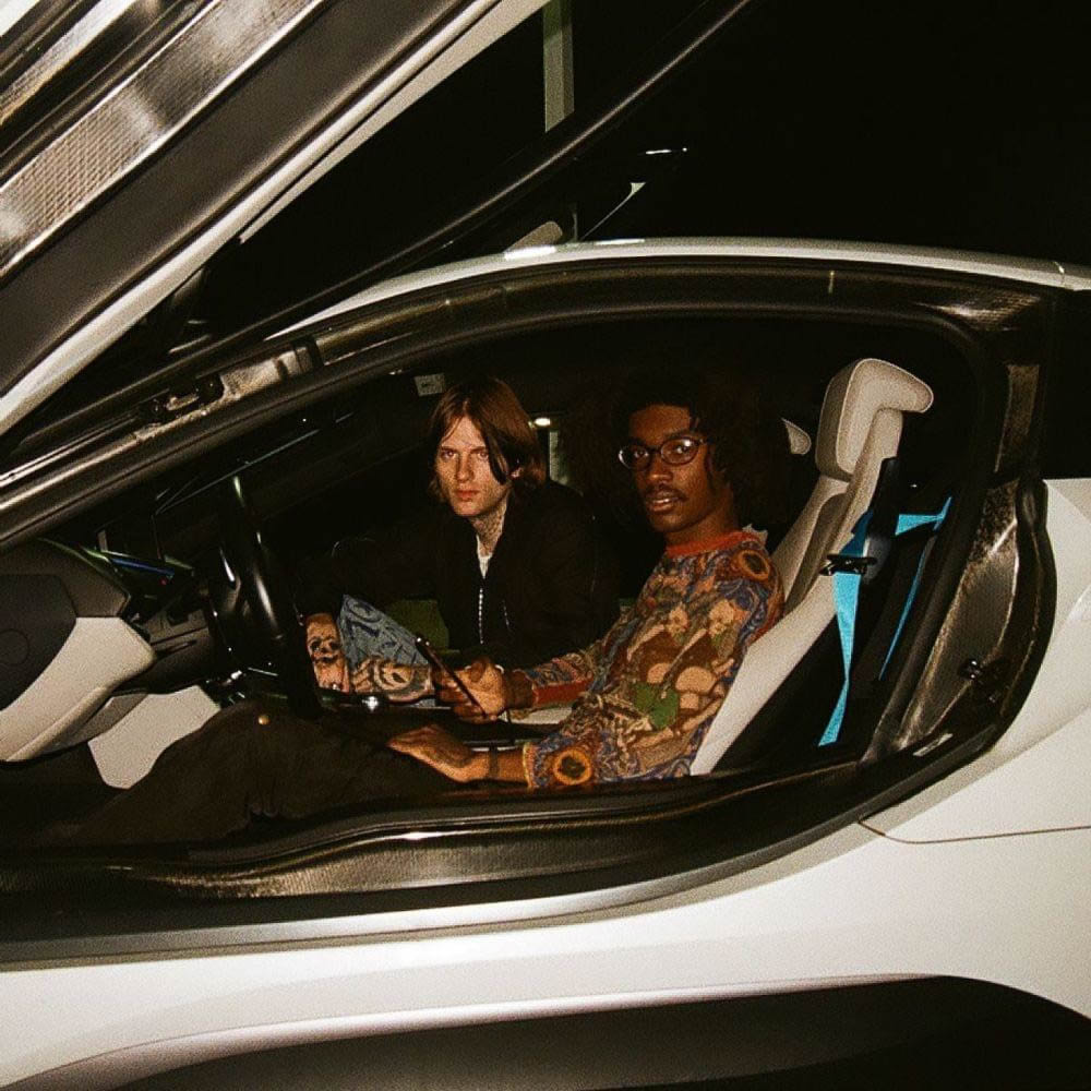 Louie Duffelbags and Boothlord sitting in a gull wing BMW