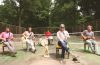 members of ROSSER sitting in chairs, playing their instruments on an old tennis court