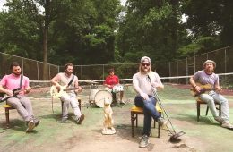 members of ROSSER sitting in chairs, playing their instruments on an old tennis court