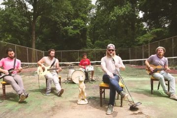 members of ROSSER sitting in chairs, playing their instruments on an old tennis court