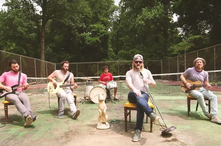 members of ROSSER sitting in chairs, playing their instruments on an old tennis court