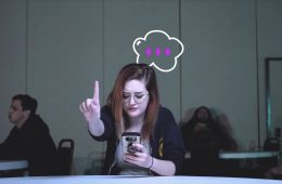 girl on a cell phone holding one finger up