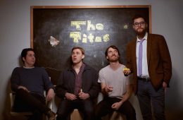 members of The Titos sitting in front of chalkboard