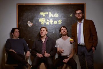 members of The Titos sitting in front of chalkboard