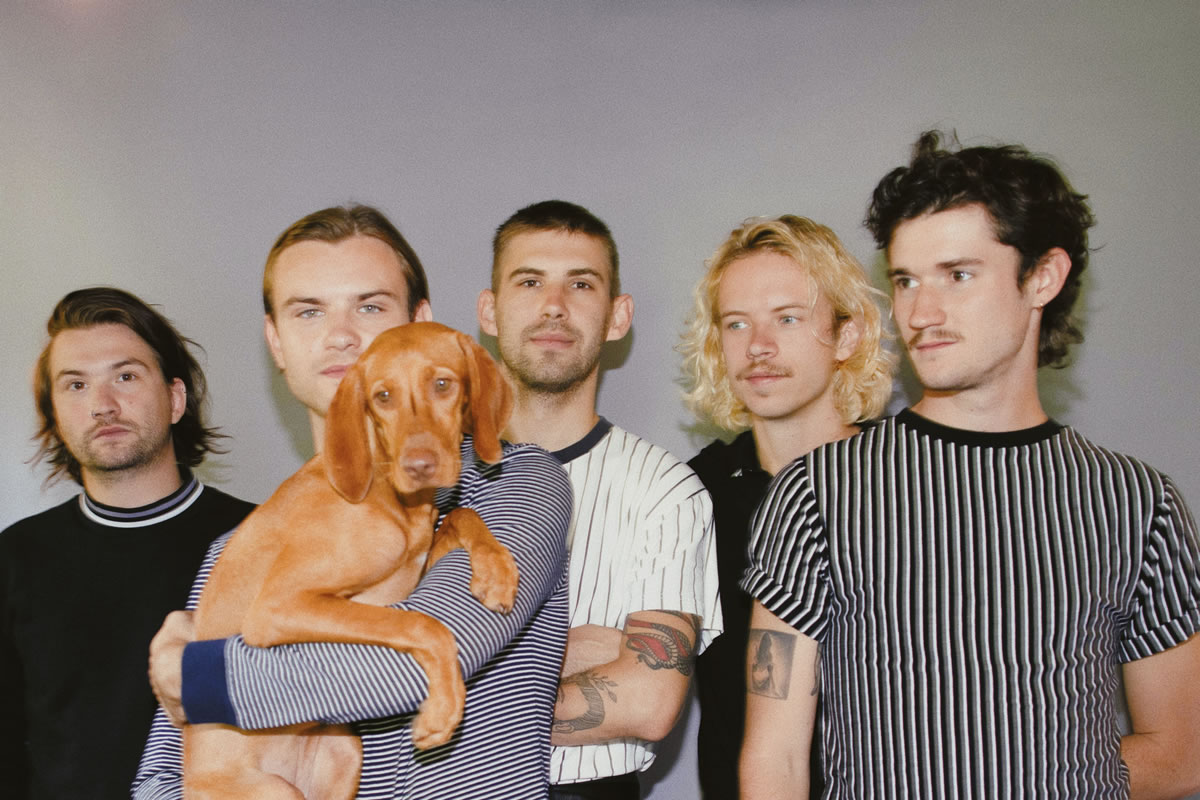 Members of Wanderwild standing in line with one member holding a dog.