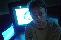 man in front of two television screens