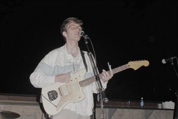 Elijah Johnston playing a guitar onstage.