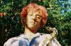 Atlanta artist Hio holding a saxophone in front of a tree