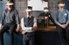 Members of Quiet Hounds wearing blindfolds and masks standing in front of a desk