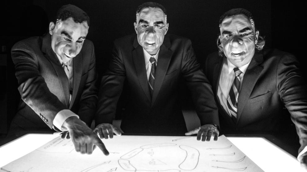 members of Victory Hands pointing at a map and wearing Richard Nixon masks