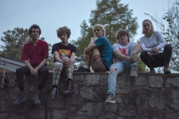 Members of Silver Lake Waves sitting on a wall.