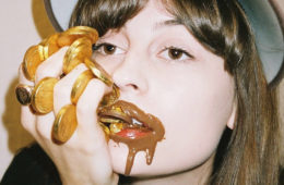 Faye Webster with mouth covered in chocolate gold coins.