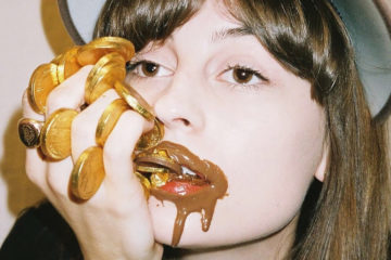 Faye Webster with mouth covered in chocolate gold coins.