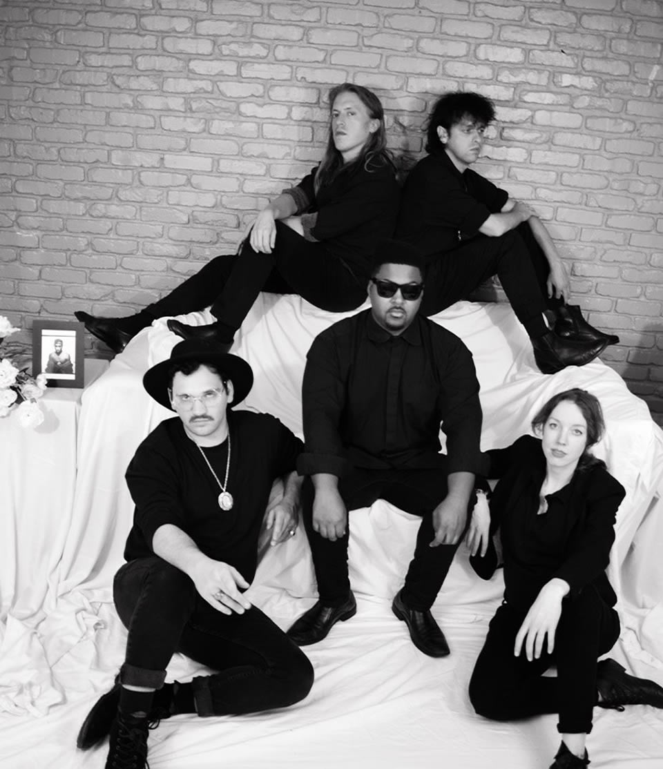 Members of Shepherds wearing all black and sitting on white cloth