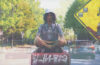 Akete sitting cross-legged next to a street sign.