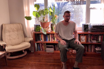 George Huntington sitting in a chair in his living room.