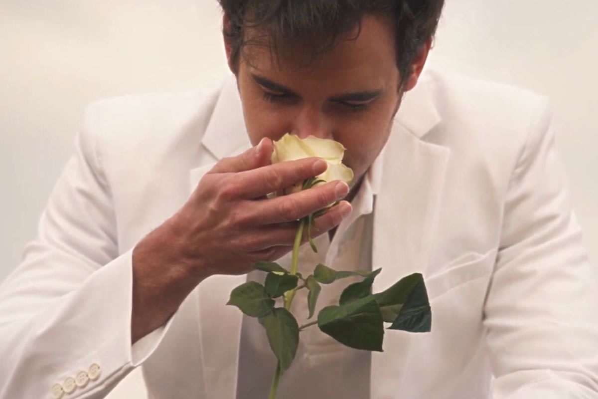 man in white suite sniffing a rose in video for The Head's Haunt Me