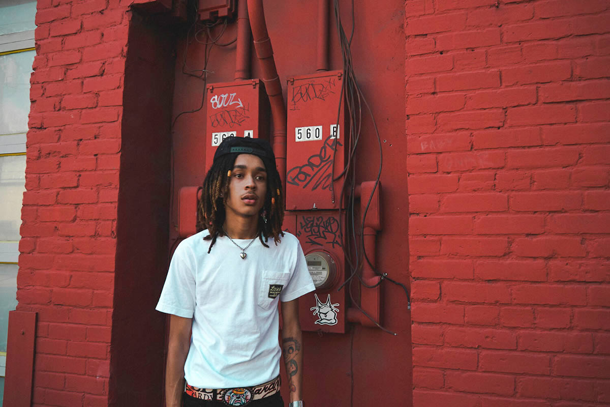 photo of Jelani Imani in front of a red wall
