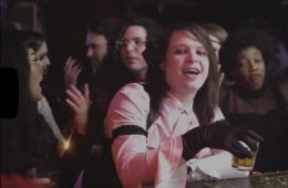 still shot of Sarah Rose holding a shot inSarah and the Safe Word's new video.