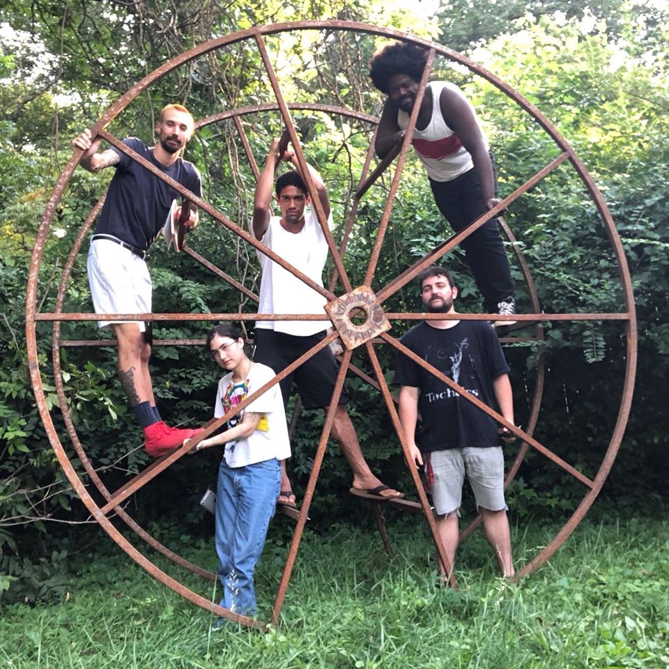 Members of The Big Heed in a giant spoked wheel