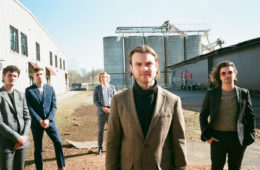 members of Wanderwild standing in a yard in front of a building.