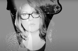 Woman wearing glasses staring through a ghosted image of a guitar.