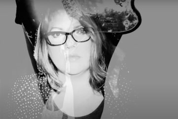 Woman wearing glasses staring through a ghosted image of a guitar.