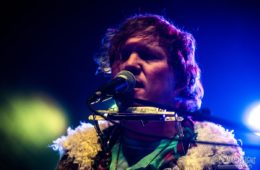 Hunter Morris singing with a harmonica around his neck