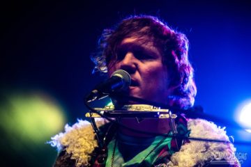 Hunter Morris singing with a harmonica around his neck