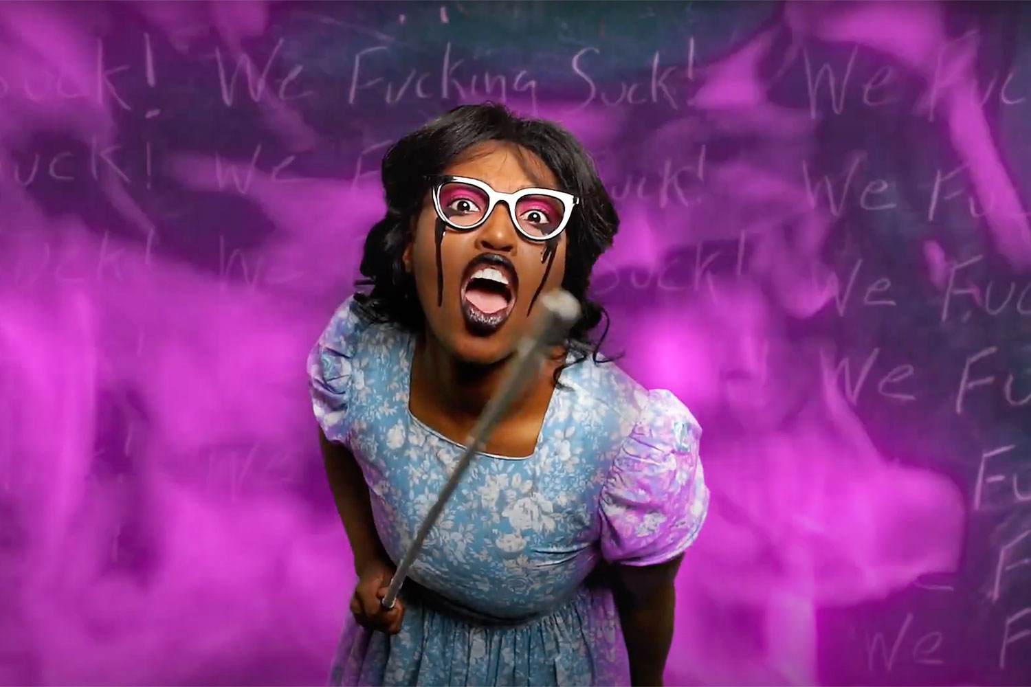 black woman with glasses holding a pointer against a purple smoke backdrop.