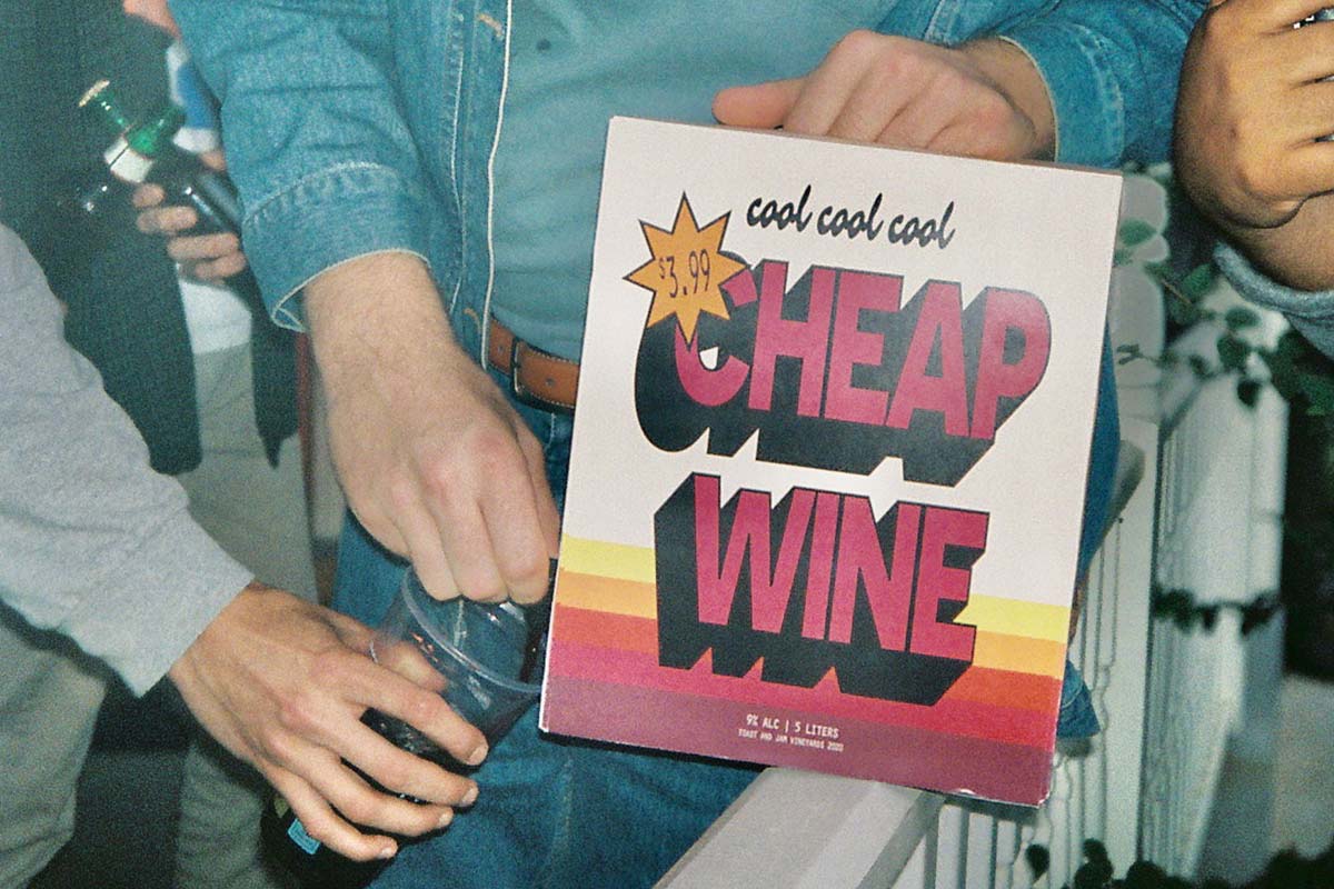Man pouring wine out of a box that reads Cool Cool Cool Cheap Wine
