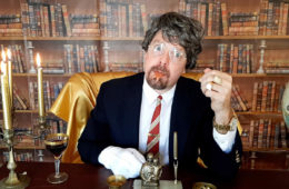 Brandon Taj Hanick of Future Lives sitting in an office wearing a white glove and smiling with a lizard tongue