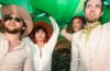 Members of Chick Wallace dressed in white and carrying a green blow up dinosaur