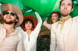 Members of Chick Wallace dressed in white and carrying a green blow up dinosaur