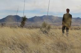Luke Smith standing in a field with mountains behind him