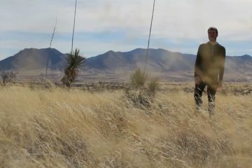 Luke Smith standing in a field with mountains behind him