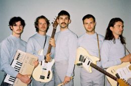 press photo of members of Wanderwild all wearing gray and holding their instruments