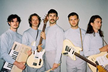 press photo of members of Wanderwild all wearing gray and holding their instruments