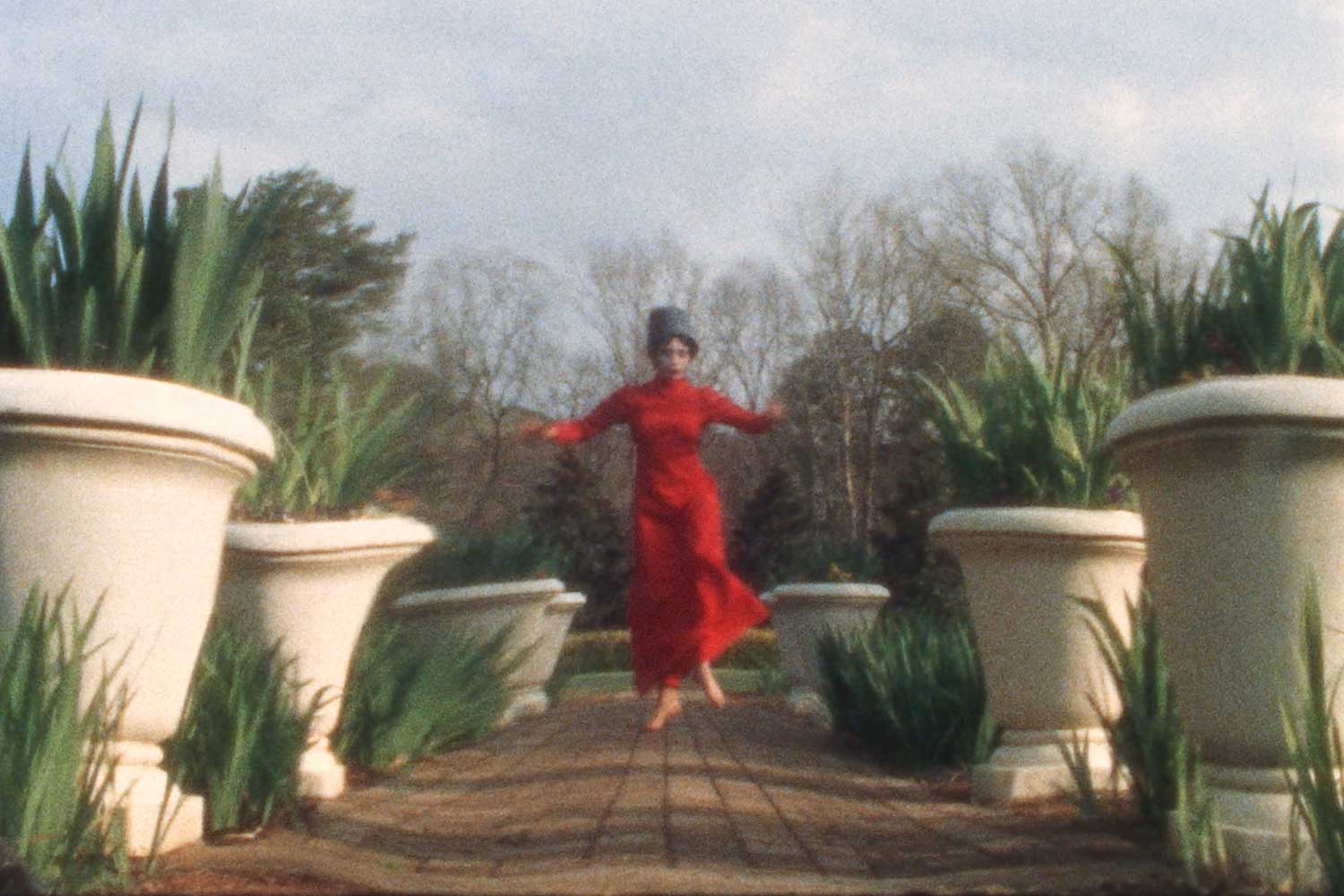 woman in red dress dancing amid white planters