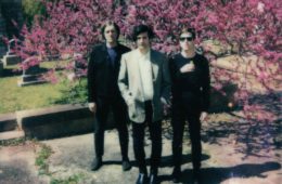 three members of Small Reactions in a cemetery