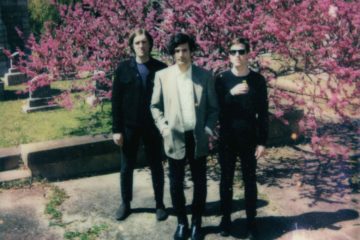 three members of Small Reactions in a cemetery
