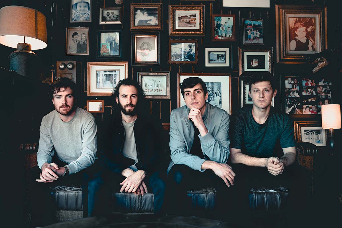 members of Walden sitting on a couch with photos behind them