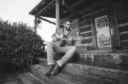 Tyler Key playing guitar on a porch
